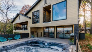 Ett modernt hus i två våningar med en stor utomhusjacuzzi och en sittgrupp.