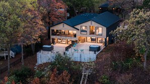 Une maison moderne à deux étages, dotée d’une grande terrasse et entourée d’arbres.