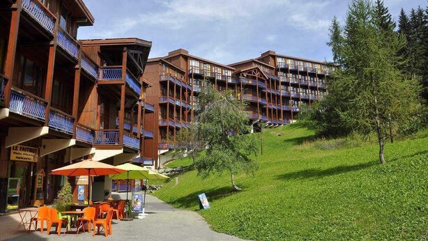 Um hotel com vários andares, varandas, área externa para sentar e um restaurante.