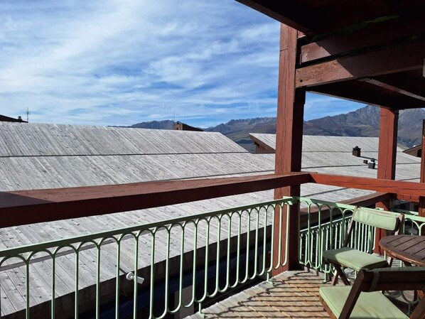 Une terrasse en bois avec une rambarde en métal, une table et des chaises.