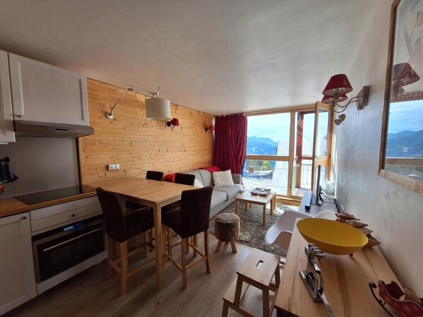 A compact living space with a kitchen, dining area, and a sofa with a view.
