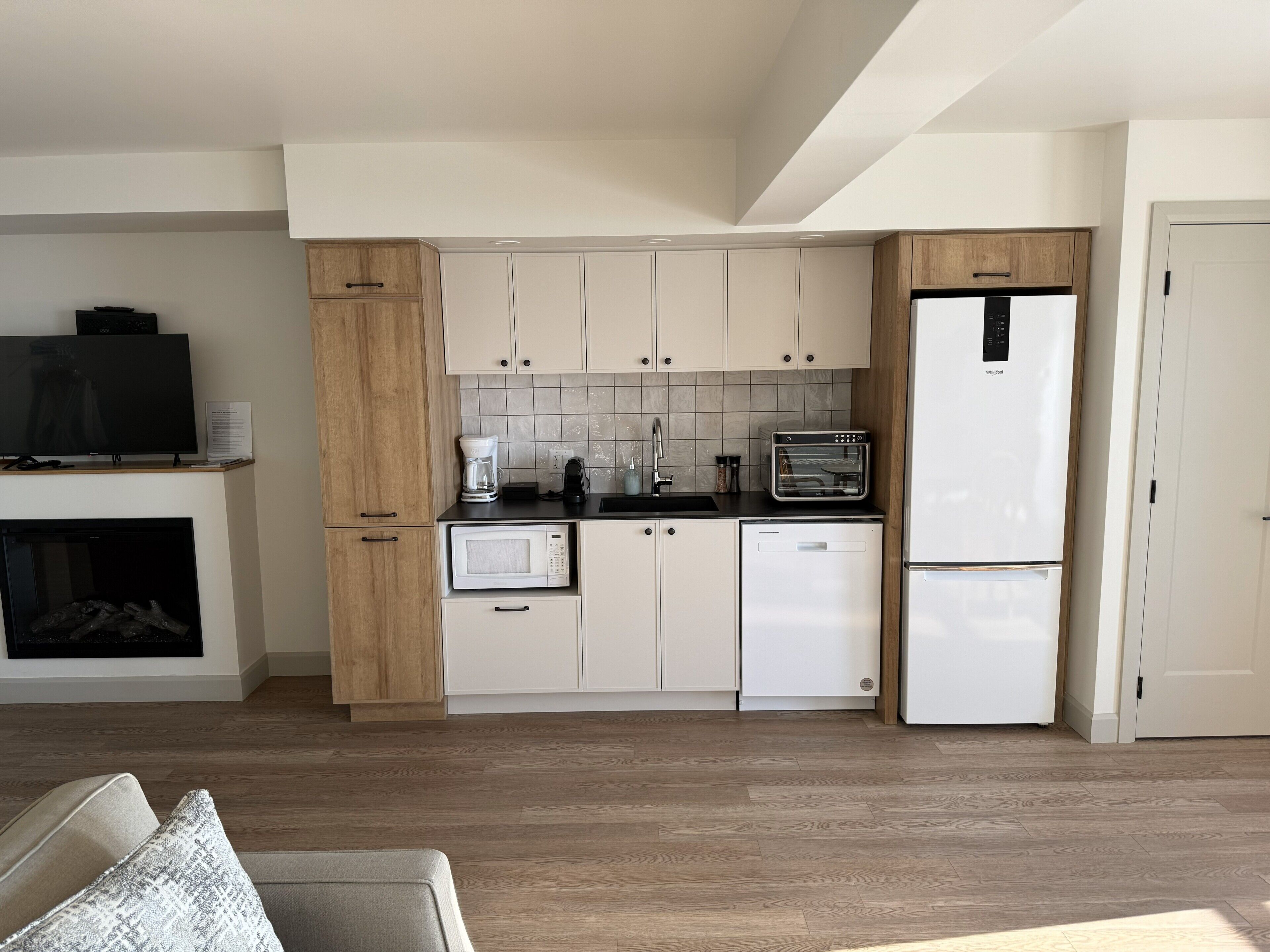 A compact kitchen with white cabinets, a microwave, a coffee maker, a toaster, and a refrigerator.