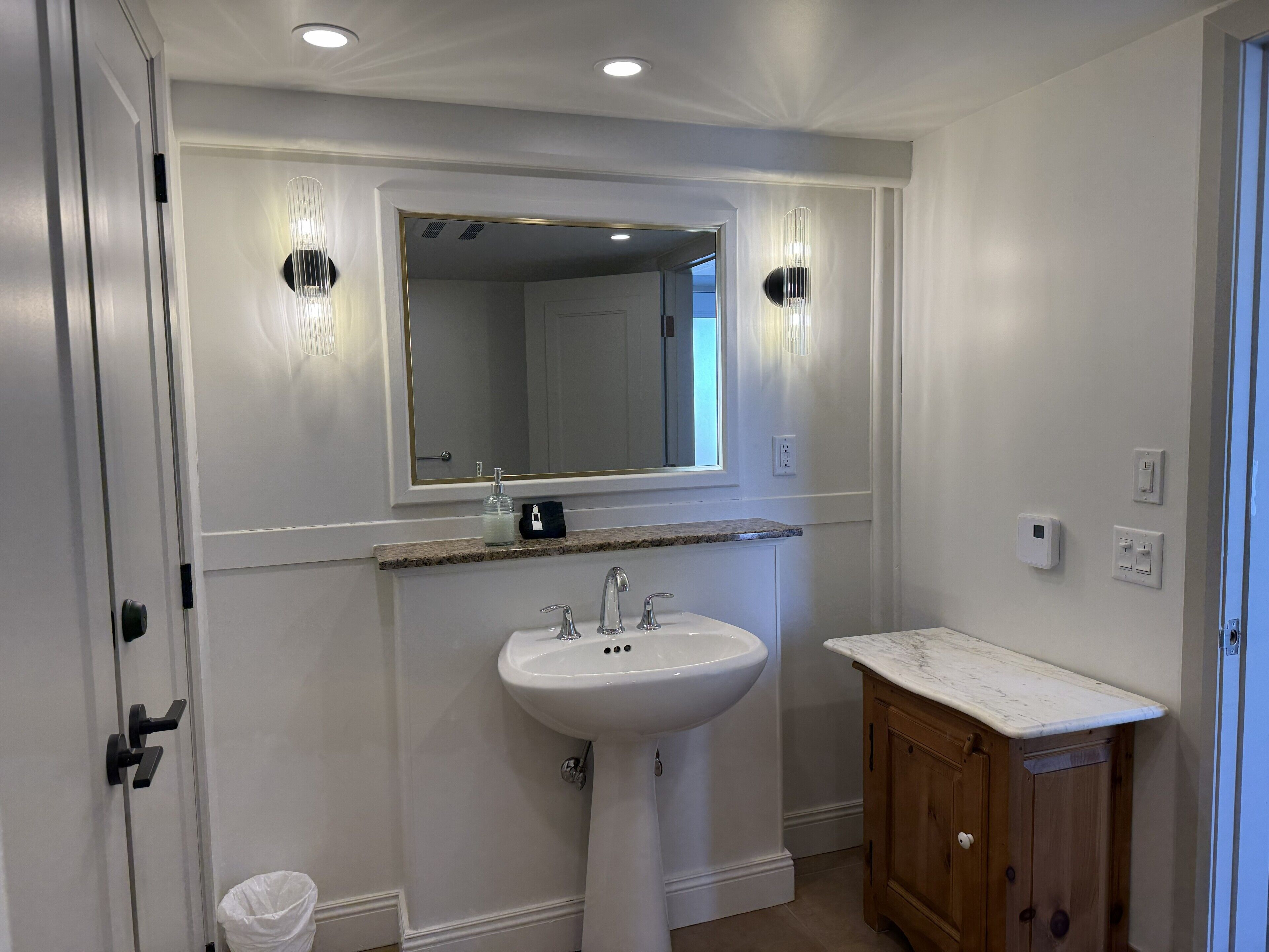 Une salle de bain avec un lavabo blanc, un miroir et des meubles en bois.
