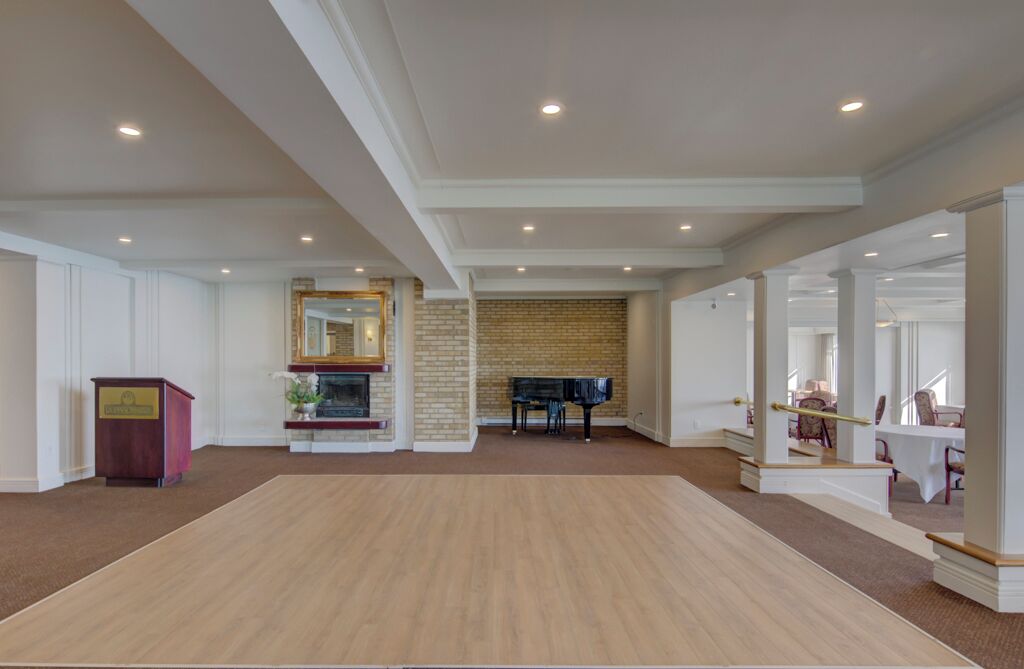 Um quarto amplo com um piano, uma lareira e um espelho grande.