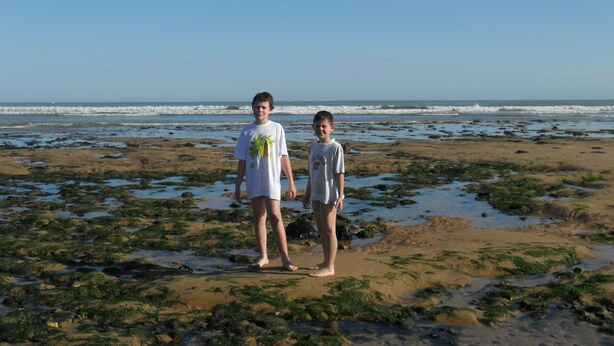 Two people standing on a beach with seaweed and rocks. - Detached house, in an enclosed garden, quiet location, near forest and sea (Saint-Vincent-sur-Jard)