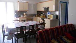 A compact kitchen with a dining table, chairs, a microwave, and a coffee maker. - Detached house, in an enclosed garden, quiet location, near forest and sea (Saint-Vincent-sur-Jard)