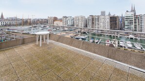 A rooftop terrace with a view of a marina and cityscape. - Sunny Apartment With Large Terrace (Ostend)