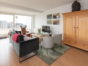 A modern living room with a sofa, armchairs, a coffee table, a TV, and a cabinet. - Sunny Apartment With Large Terrace (Ostend)
