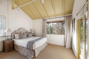 A bedroom with a bed, bedside tables, a window with curtains, and a ceiling fan.
