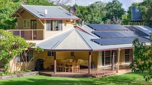 Ein zweistöckiges Haus mit einer Veranda, Solaranlagen auf dem Dach und einer Satellitenschüssel.