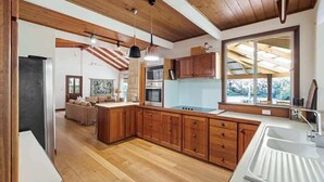 Una cucina moderna con mobili in legno, una grande isola e luci a sospensione.