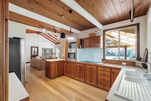 Eine moderne Küche mit Holzschränken, einer großen Kochinsel und Pendelleuchten.