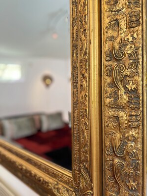 A close-up of an ornate, gold-framed mirror with intricate designs. - villa de nachtegaal (Naarden)