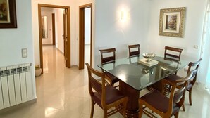 A dining area with a glass table and wooden chairs, a radiator, and a framed picture on the wall. - Stunning Town Villa close to beach and Golf courses (Caldas da Rainha)