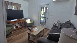 Un salon avec une lucarne, un téléviseur, un canapé, une table basse et une porte.