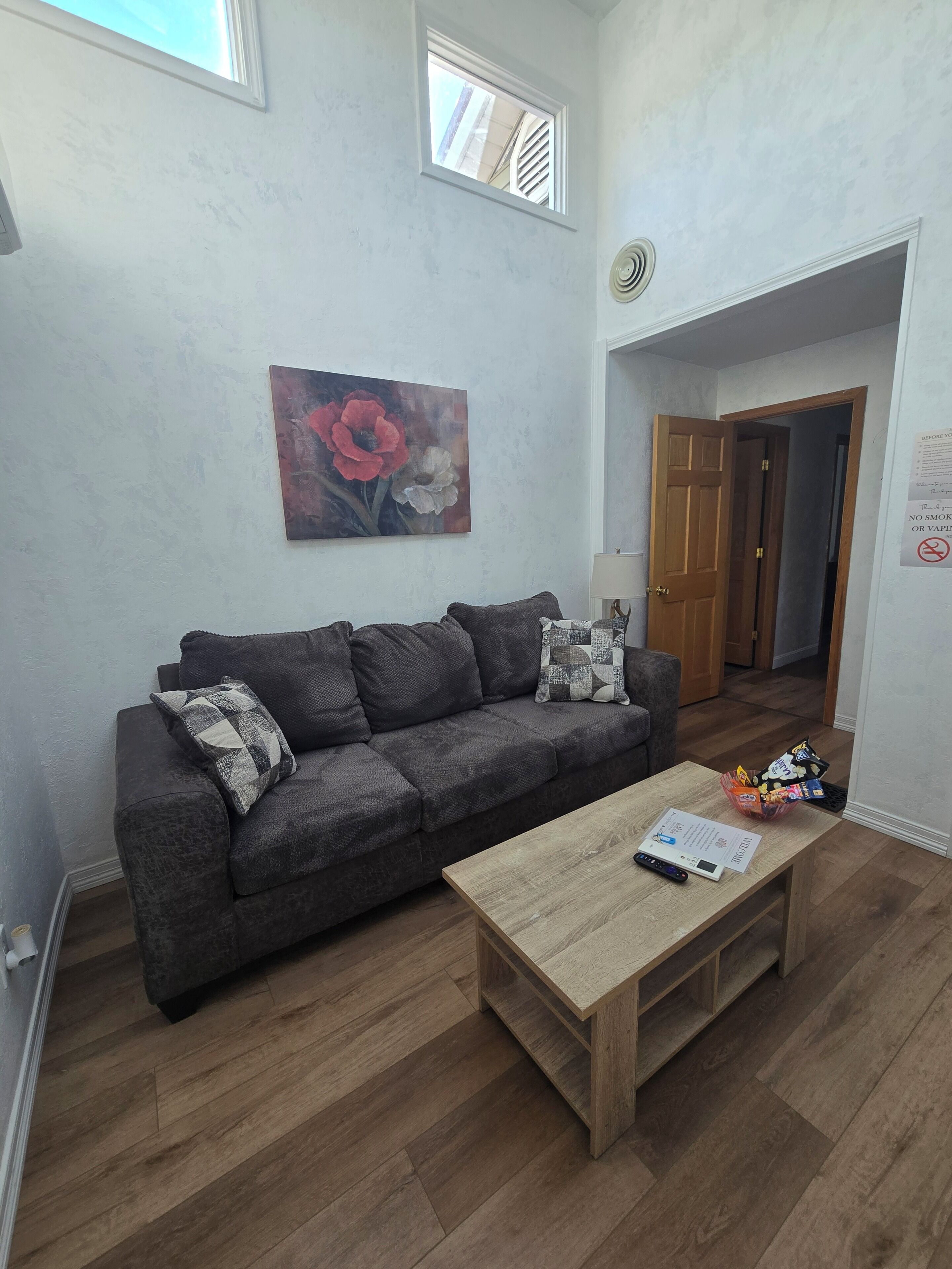 Una sala de estar con un sofá gris, una mesa de centro de madera y un cuadro en la pared.