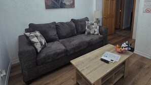 Ein Wohnzimmer mit grauem Sofa, einem Holztisch und einem Gemälde an der Wand.