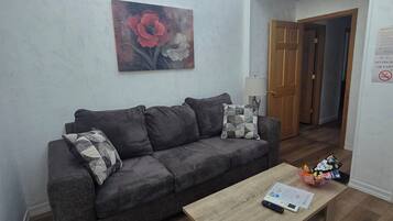 Una sala de estar con un sofá gris, una mesa de centro de madera y un cuadro en la pared.