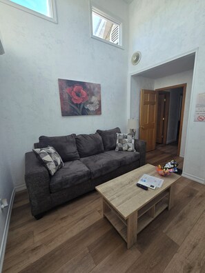 Ein Wohnzimmer mit grauem Sofa, einem Holztisch und einem Gemälde an der Wand.