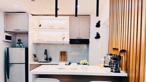 A modern kitchen with white cabinetry, a central island with seating, and a wooden accent wall. - 2bedroom condo in enjoyable Quezon City with WiFi, AC (Quezon City)