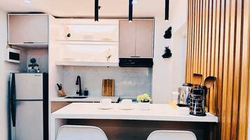 A modern kitchen with white cabinetry, a central island with seating, and a wooden accent wall.
