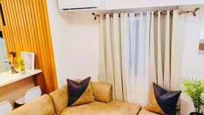 A modern living room with a sectional sofa, a small table, and a potted plant. - 2bedroom condo in enjoyable Quezon City with WiFi, AC (Quezon City)