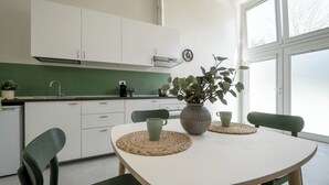 Une cuisine moderne avec des meubles blancs, un plan de travail vert et une table à manger avec des chaises.