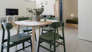 Une pièce moderne et bien éclairée, comprenant une table à manger, des chaises, un téléviseur et un lit.