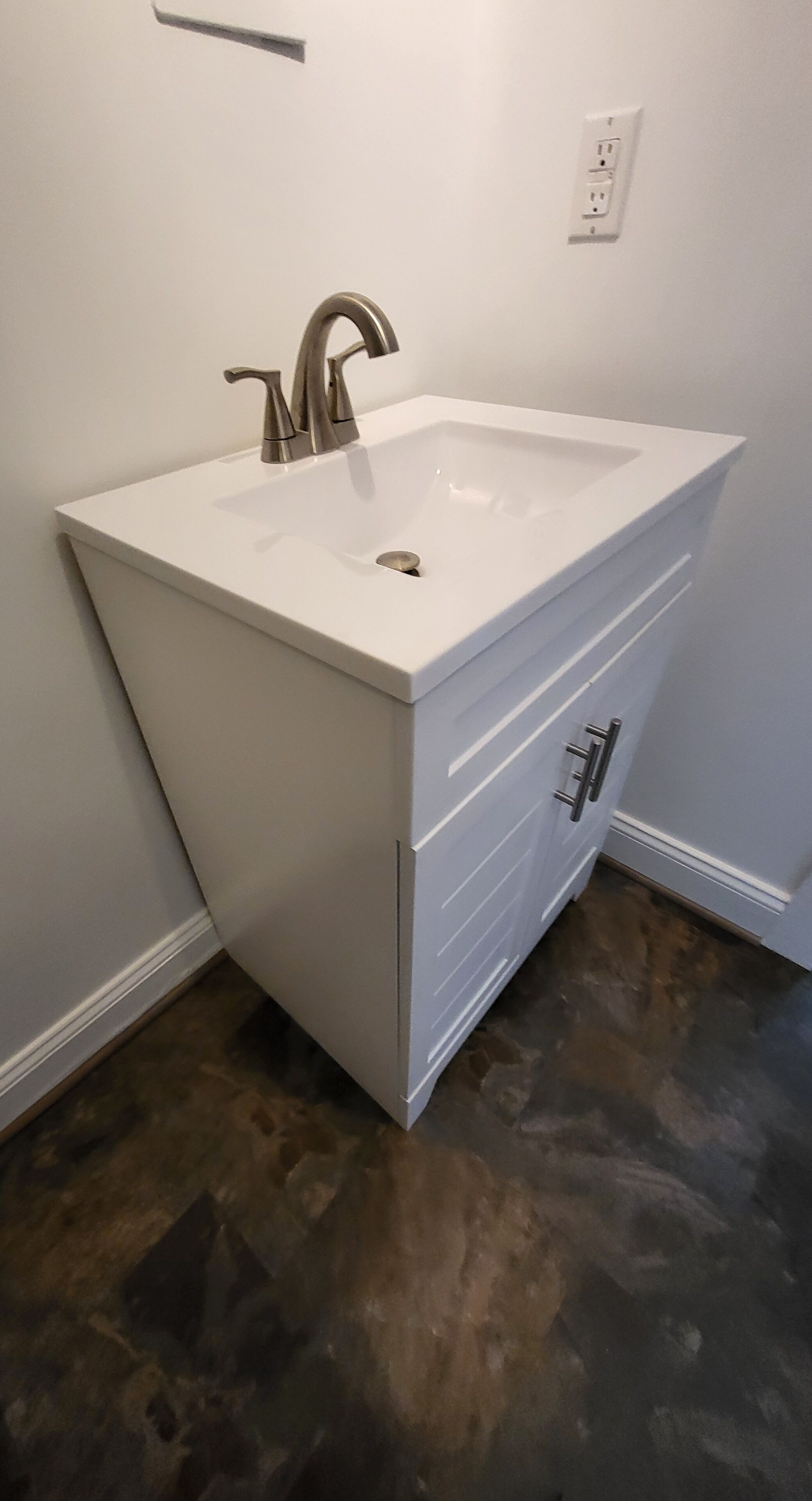 A bathroom with a white sink, a mirror, and a wall-mounted electrical outlet.