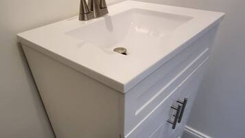 A bathroom with a white sink, a mirror, and a wall-mounted electrical outlet.