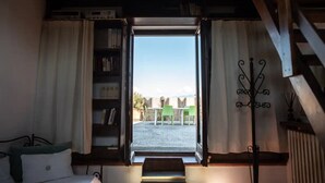 Una habitación con un ventanal grande, una estantería, una cama y una escalera.