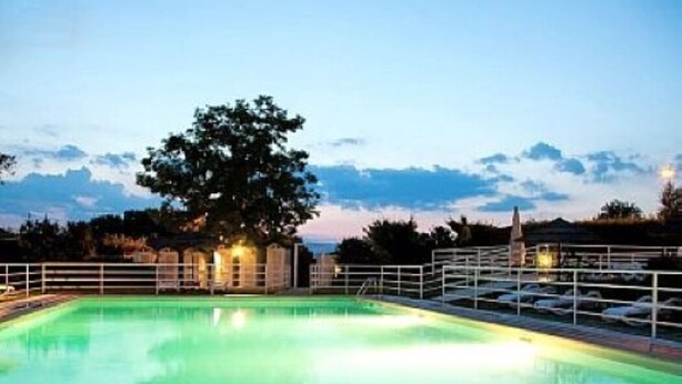 Una piscina con un árbol en el centro, rodeada por una valla y una barandilla.
