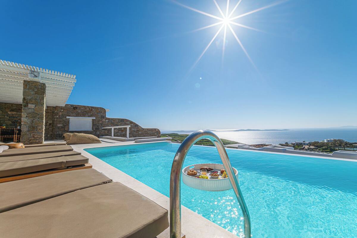 Una piscina con zona de solárium y vistas al mar.