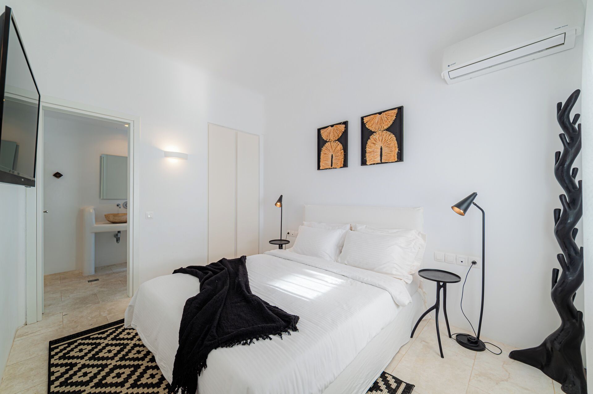 A modern bedroom with a bed, bedside tables, a mirror, and artwork on the wall.