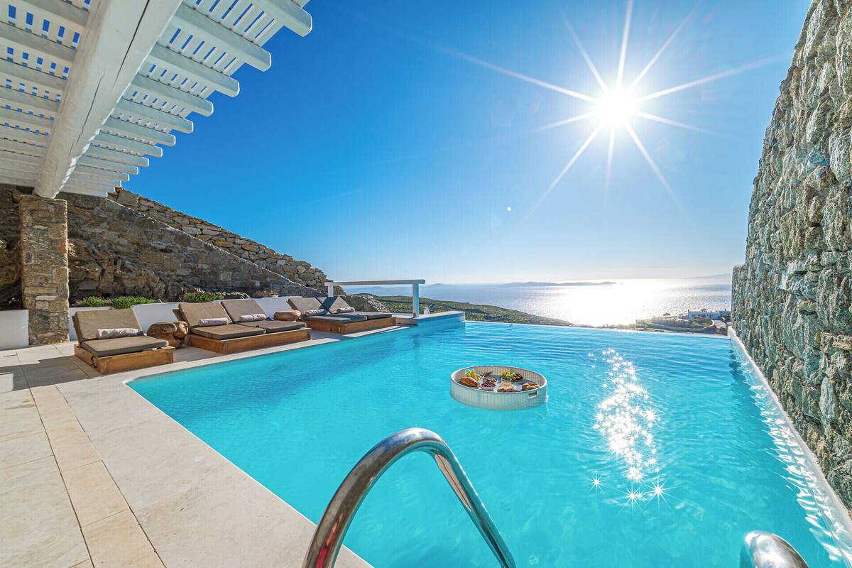 Una piscina con sillas de descanso y vistas al mar.