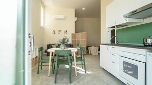 Une cuisine compacte avec des meubles blancs, une cuisinière et un coin repas comprenant une table et des chaises.