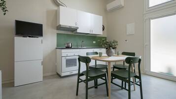 Una cucina moderna con mobili bianchi, forno integrato, lavello e zona pranzo con tavolo e sedie.
