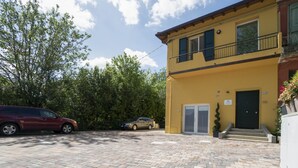 Un bâtiment jaune doté d’un balcon, d’une porte et d’un petit jardin.