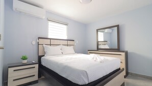 A modern bedroom with a bed, bedside tables, a mirror, and a potted plant. - Casa Mar Y Sol - Vistamar, PR –  4 Minutes From Airport and 8 minutes to Beaches (Carolina)