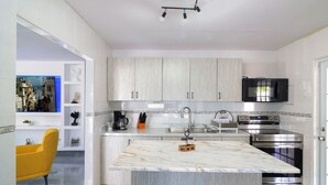 A modern kitchen with a marble island, stainless steel appliances, and light wood cabinets. - Casa Mar Y Sol - Vistamar, PR –  4 Minutes From Airport and 8 minutes to Beaches (Carolina)