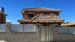 A two-story house with a tiled roof, a gated entrance, and a satellite dish. - Habitacion Monteazul (El Casar)
