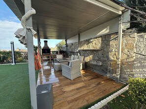 An outdoor patio with a stone wall, wicker furniture, and a brick oven. - Habitacion Monteazul (El Casar)