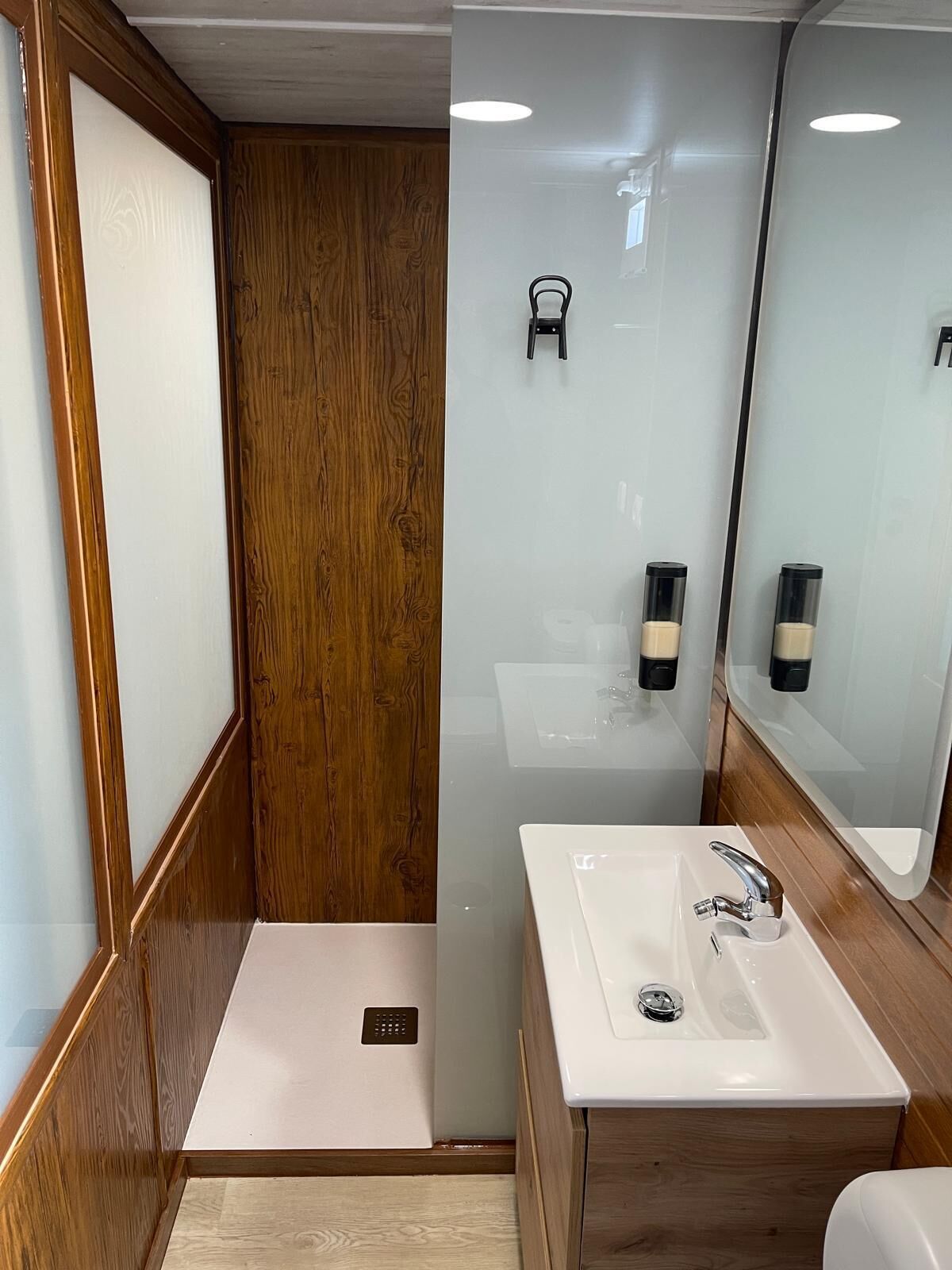 A modern bathroom with a wooden vanity, a white sink, and a mirror.