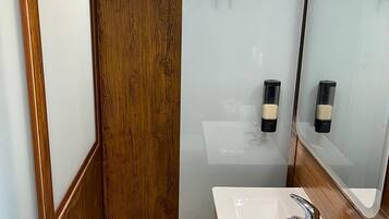 A modern bathroom with a wooden vanity, a white sink, and a mirror.