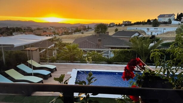 A residential area with a swimming pool, lounge chairs, and a sunset view. - Habitacion Monteazul (El Casar)