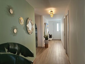 Stylish hallway with a light-colored floor, decorative mirrors, and a potted plant.