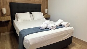 A neatly made bed with white linens and a dark headboard, flanked by two bedside tables with lamps. - Habitacion Monteazul (El Casar)