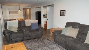 Ein Wohnzimmer mit zwei dunklen Ledersofas, einem Holztisch und einem gemusterten Teppich.