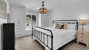 Un dormitorio con cama, mesita de noche de madera, cómoda y ventana con vistas.