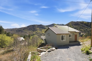 A small, single-story building with a metal roof, a front porch, and a staircase leading to a deck. - Rose Canyon Lake Cabin at Mt. Lemmon Hotel Overlooking Summerhaven, Arizona (Mount Lemmon)